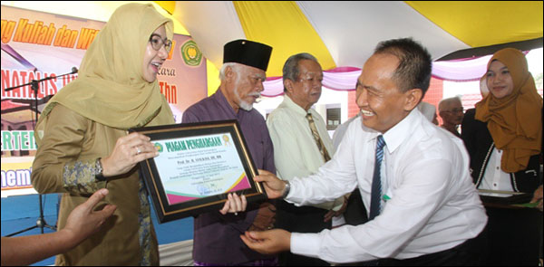 Rektor Unikarta Dr Sabran SE MSi menyerahkan penghargaan untuk mantan Rektor Unikarta H Syaukani HR yang diwakili oleh Bupati Rita Widyasari 