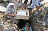 Sisa-sisa jasad dibungkus kain putih dan dimasukkan ke dalam peti kecil untuk dikebumikan di kuburan Muslimin Tanjung Kupang, Kelurahan Timbau