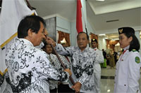 Ketua PGRI Kukar yang baru, Yonathan Palinggi, menerima bendera organisasi dari Wakil Ketua Umum PGRI Kaltim Sutomo AW