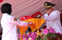 Pj Bupati Kukar Chairil Anwar menyerahkan Sang Merah Putih kepada siswi SMKN 1 Tenggarong Aprilia Happy Ariani