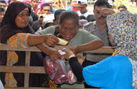 Petugas menyerahkan kantong plastik berisi daging kurban kepada warga yang telah mendapatkan kupon