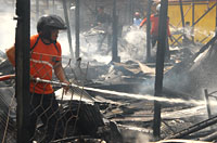 Petugas PMK memadamkan bara api di puing-puing kebakaran
