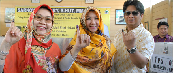Bupati Rita Widyasari bersama ibunda dan sang suami menunjukkan jari yang telah dibubuhi tinta usai mencoblos di TPS 3 Panji