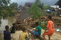 Anak-anak desa Sebulu Ilir duduk di jalan semenisasi sambil menyaksikan kawasan longsor akibat abrasi sungai Mahakam
