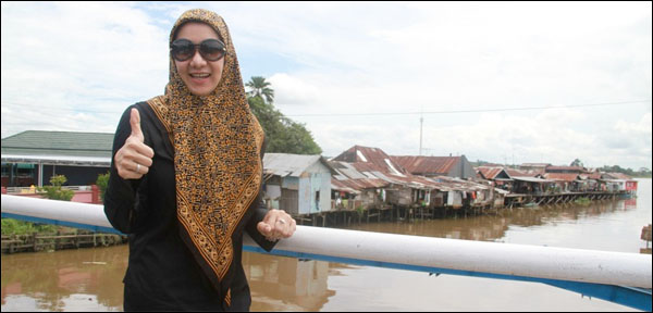 Bupati Kukar Rita Widyasari dengan latar belakang pemukian Tanjong yang akan digusur pada akhir Desember 2013