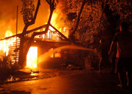 Sebuah rumah yang berada persis di depan Jalan Rondong Demang dalam keadaan terbakar hebat