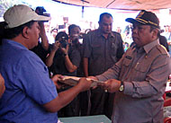 Wabup Samsuri Aspar (kanan) saat menyerahkan bantuan uang tunai dari Pemkab Kukar kepada Jumadi selaku Komandan Posko Bantuan Kebakaran Desa Segihan