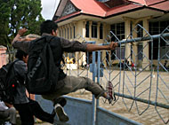 Salah seorang mahasiswa menerjang pintu pagar kampus Unikarta yang masih dalam keadaan dirantai